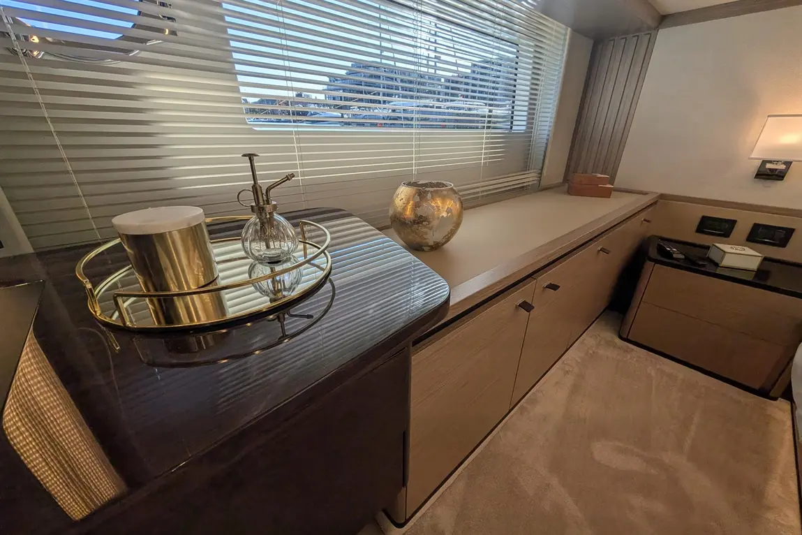 Stylish interior featuring a tray with a candle and a glass spray bottle on a marble countertop near a window with blinds.